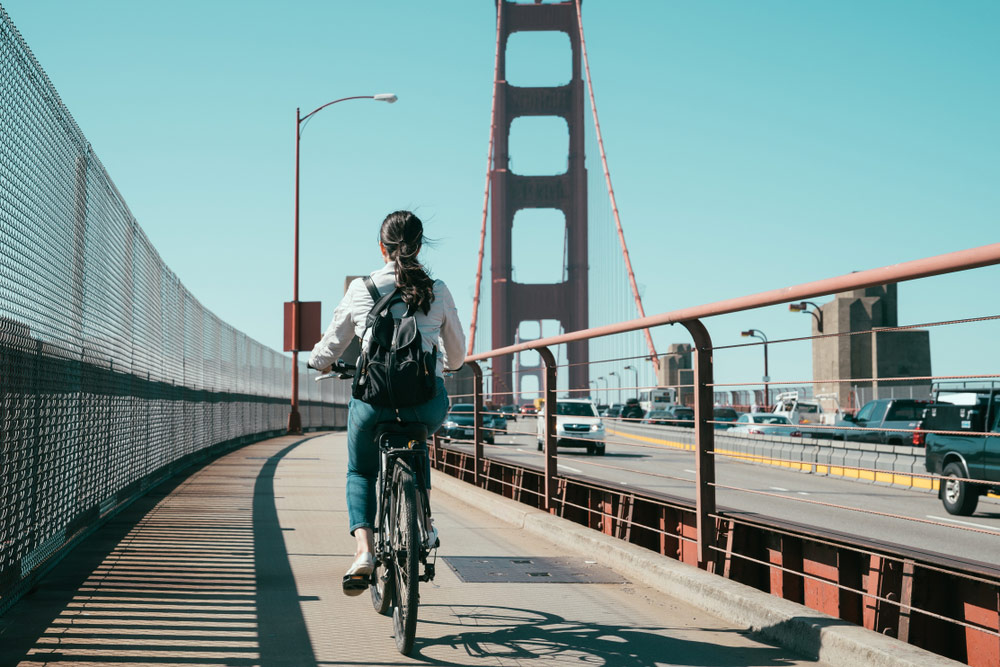 Woman biking on sidewalk on Golden Gate Bridge